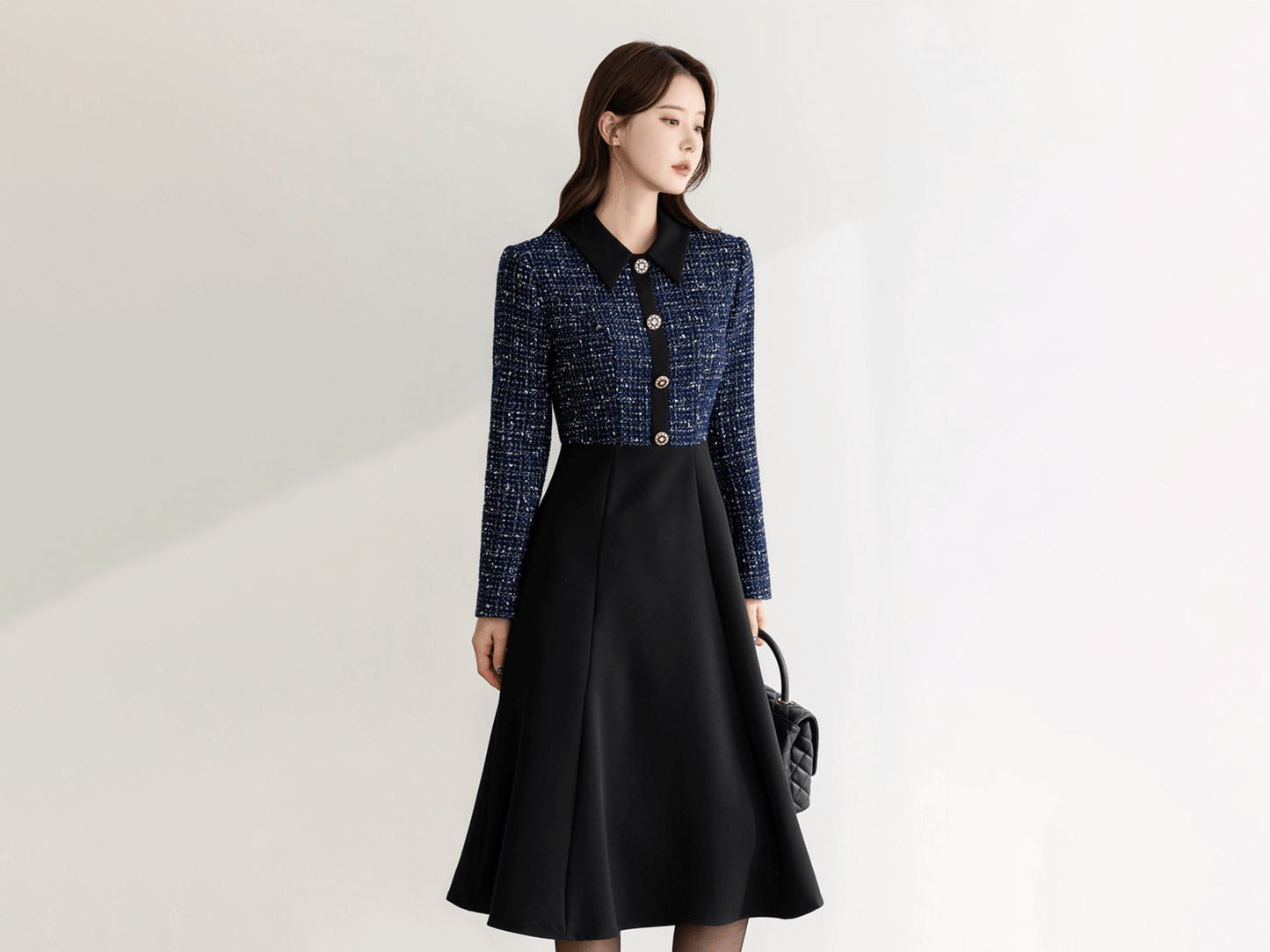 Alt Tag: Elegant two-tone tweed and black flare dress with gold button detail, featuring navy tweed top and smooth black skirt.