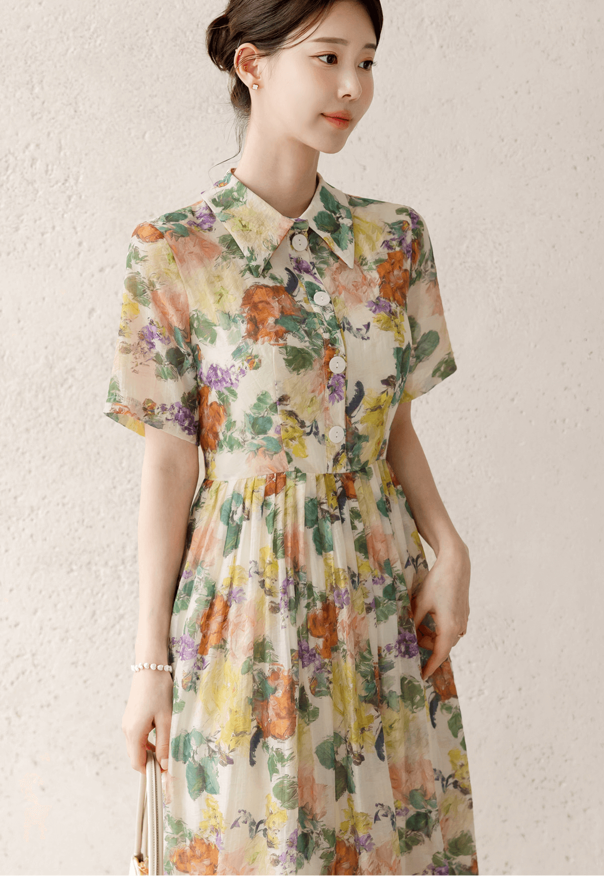 Woman wearing a romantic floral dress with pintuck details and a collar neckline, showcasing soft flare silhouette and textured design.