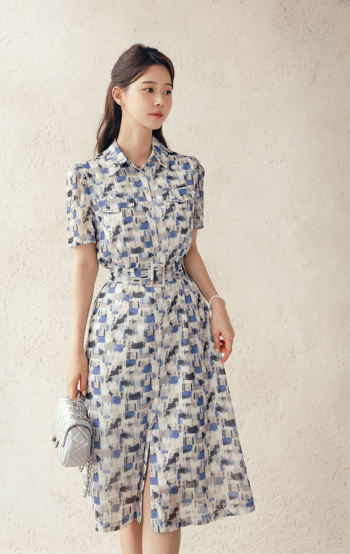 Woman wearing breezy chiffon shirt dress with belt and abstract blue pattern, embodying a fresh, vacation-ready look.