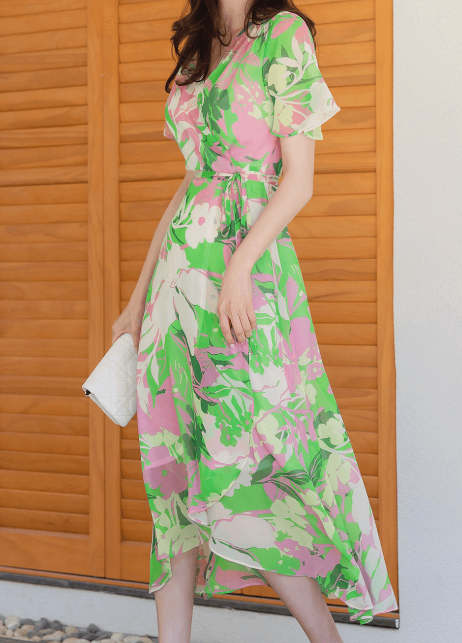Woman wearing a chiffon wrap dress with tulip hem, featuring large floral patterns in pink and green, ideal for breezy, feminine style.