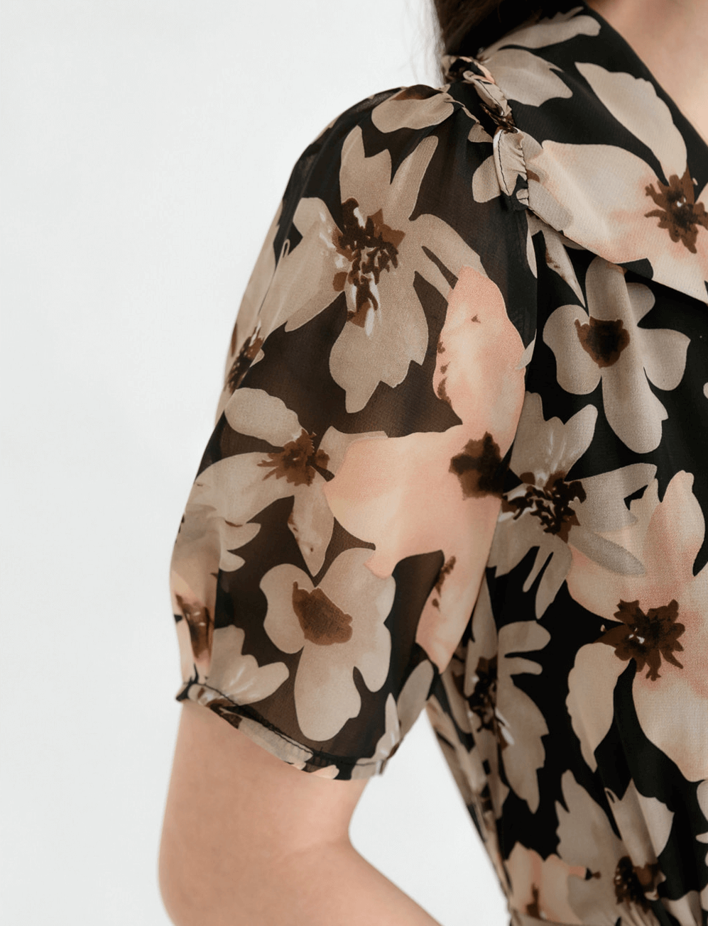 Close-up of floral chiffon dress with wide flat collar and puff short sleeves, showcasing elegant design and feminine style.