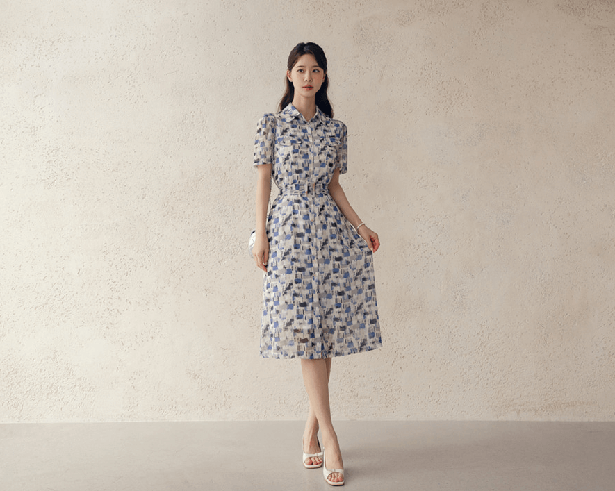 Model wearing breezy chiffon shirt dress with belt, abstract blue and white pattern, collar neckline, and short sleeves, perfect for summer.