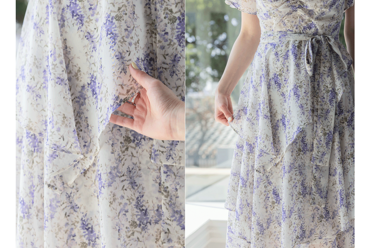 Woman wearing an asymmetrical tiered floral chiffon dress with purple blossoms, highlighting ruffle details and waist tie.