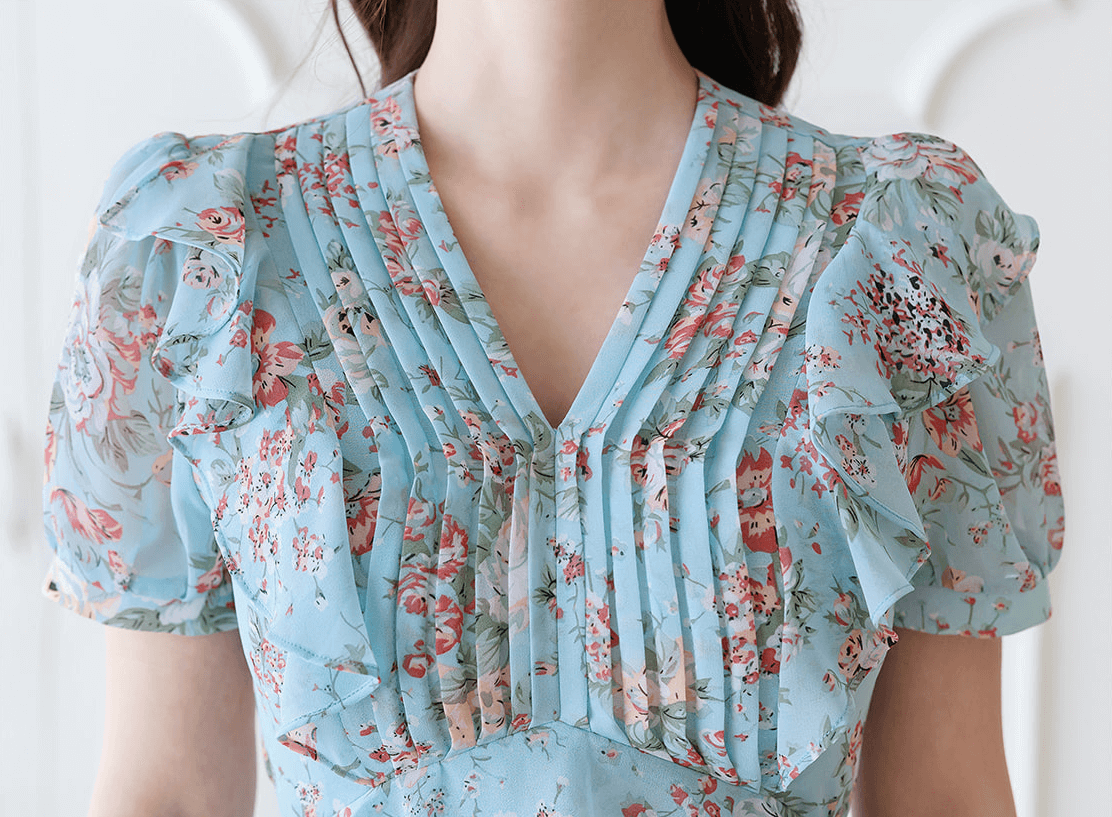 Light blue floral chiffon dress with pintuck bodice and peplum detail, featuring puffed sleeves and V-neckline for elegant style.