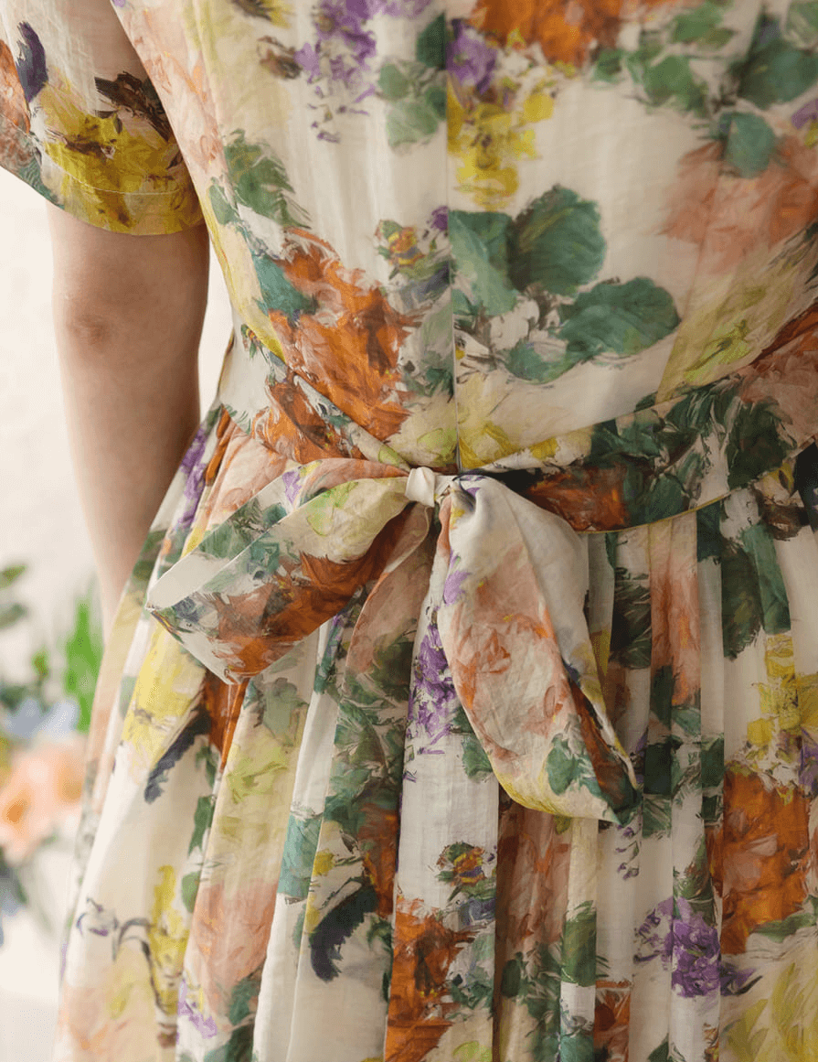 Back view of a romantic floral dress with pintuck detail, featuring vibrant flowers and bow tie, showcasing elegance and feminine style.