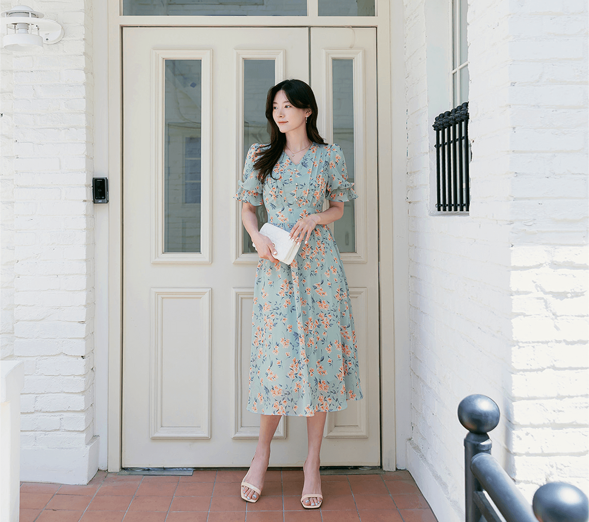 Woman in V-neck floral chiffon dress with puff sleeves, standing in breezy blue print. Ideal for spring and summer fashion.
