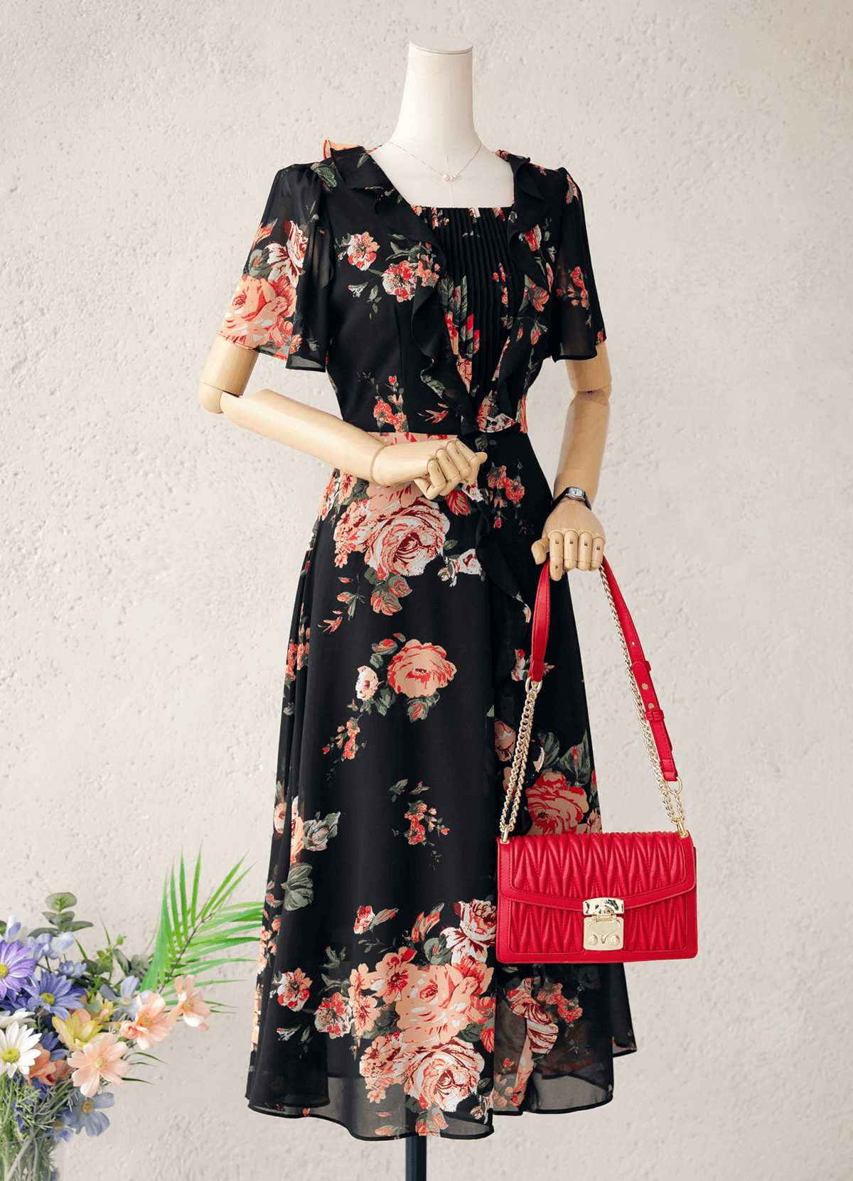 Floral chiffon dress with sheer wing sleeves and a square neckline, featuring a black base and red floral pattern, styled with red handbag.