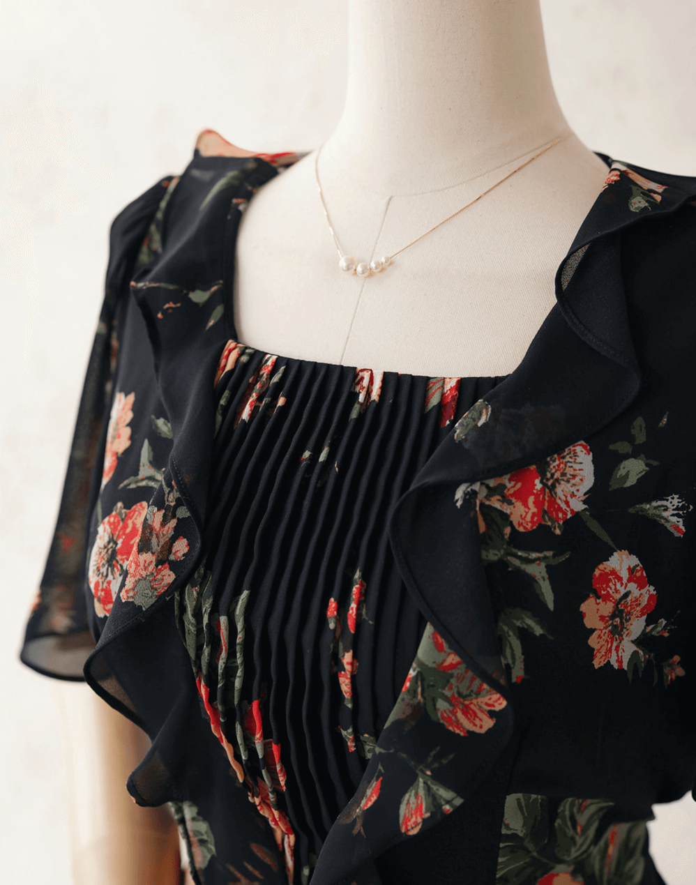 Floral chiffon dress with sheer wing sleeves, square neckline, and pleated bodice on a mannequin.