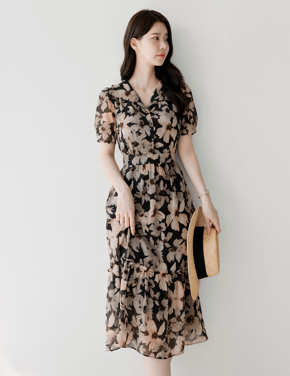 Woman wearing floral chiffon dress with wide flat collar and puff sleeves, holding a hat, showcasing feminine and airy design.