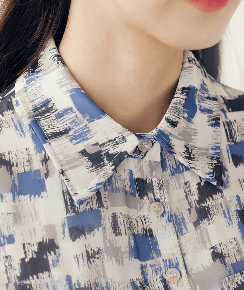 Close-up of a blue abstract patterned chiffon shirt dress with collar and buttons, highlighting the summery design.