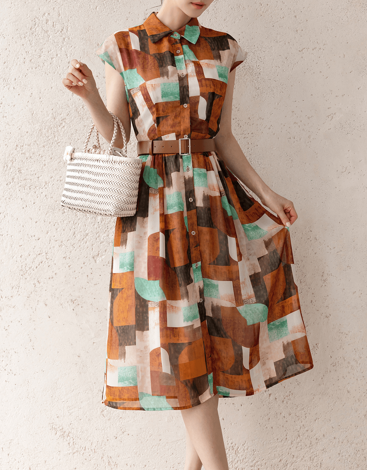 Colorful shirt dress with cap sleeves, classic collar, faux leather belt, and side pockets, styled with a woven bag against a neutral background.