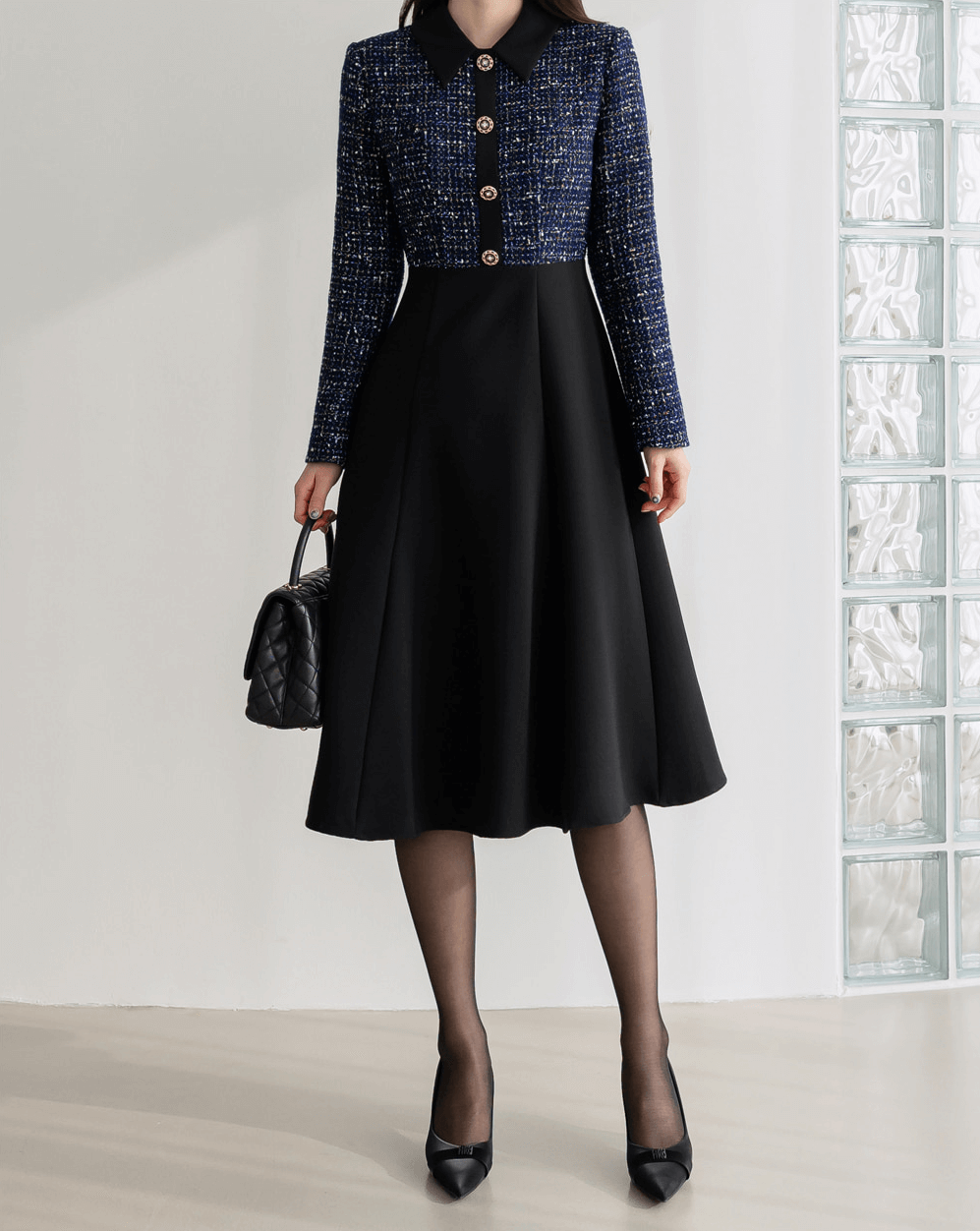 Two-tone tweed and black flare dress with gold button detail, navy tweed top, black skirt, elegant and sophisticated design.