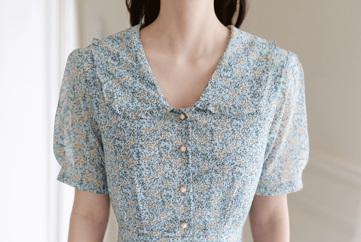 Romantic floral chiffon dress with frill collar and short sleeves, featuring waist ribbon details and soft floral print elegance.