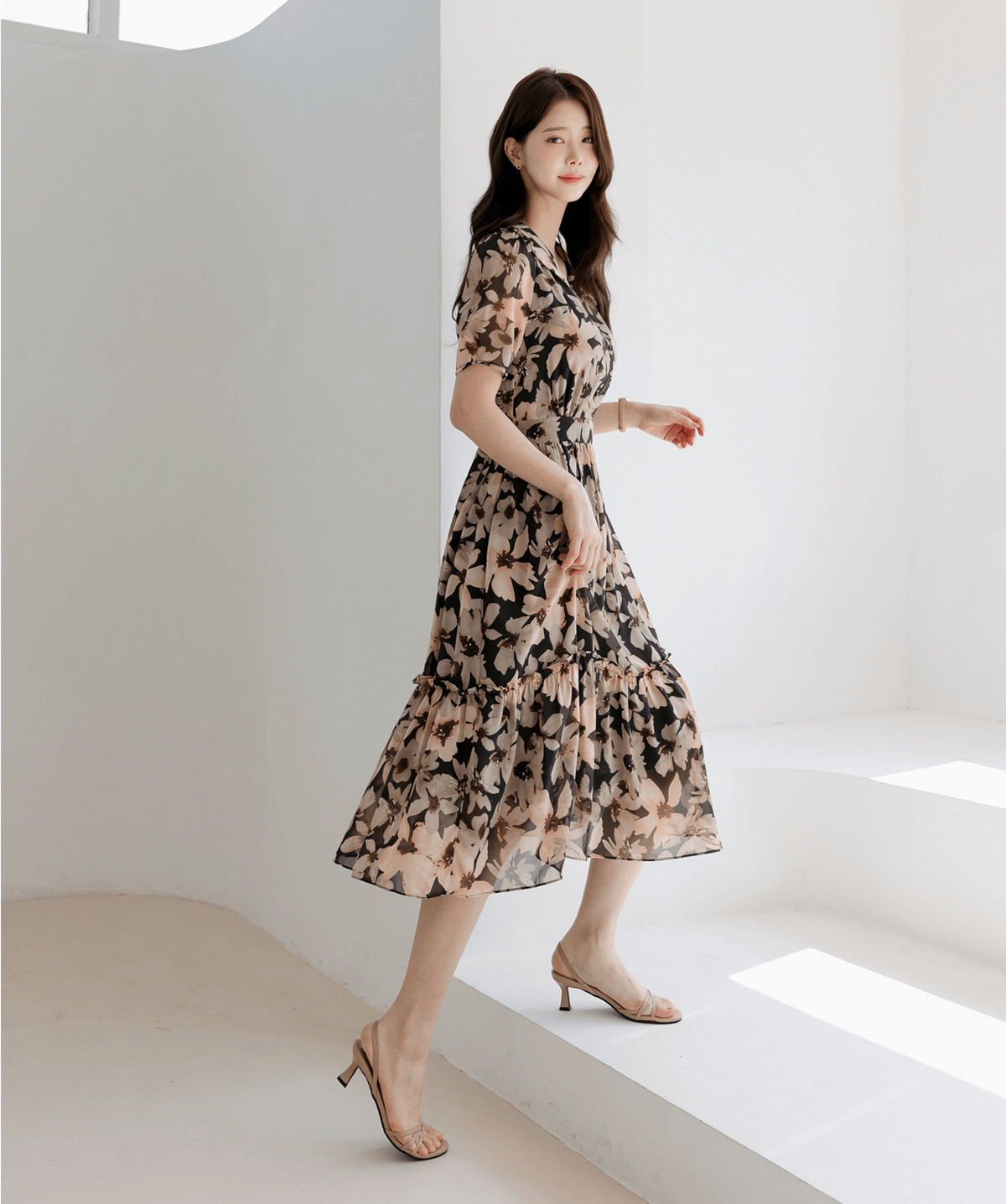 Woman wearing floral chiffon dress with wide flat collar and puff short sleeves, side view, walking gracefully in bright room.