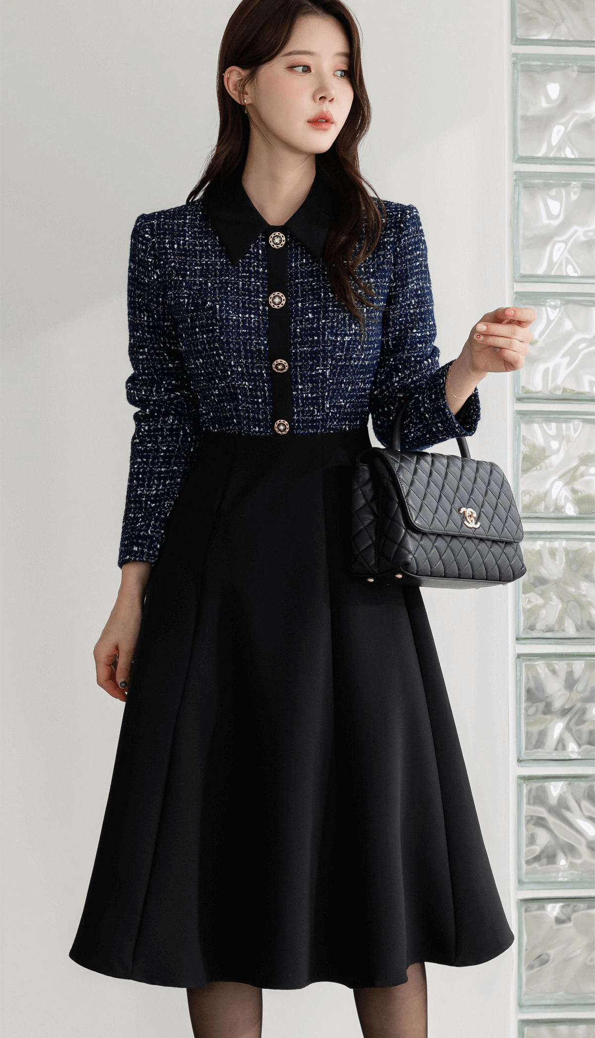 Two-tone tweed and black flare dress with gold button detail, featuring navy tweed top and smooth black skirt for a refined look.