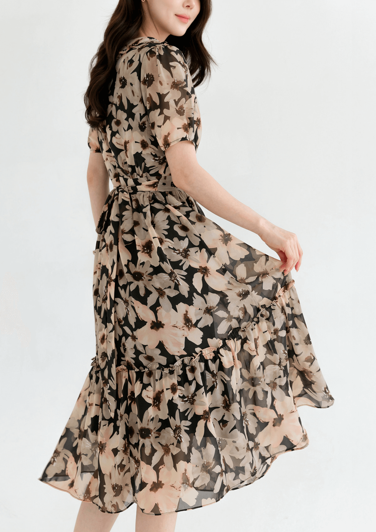 Woman wearing a floral chiffon dress with wide flat collar and puff short sleeves, showcasing an airy, feminine silhouette.