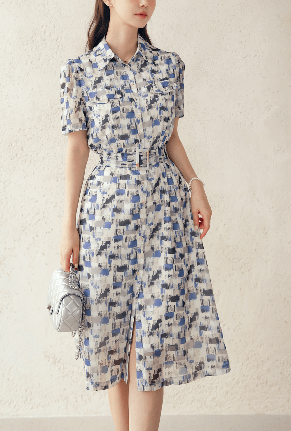 Woman wearing a blue abstract patterned breezy chiffon shirt dress with belt, perfect summer outfit for an elegant, casual look.