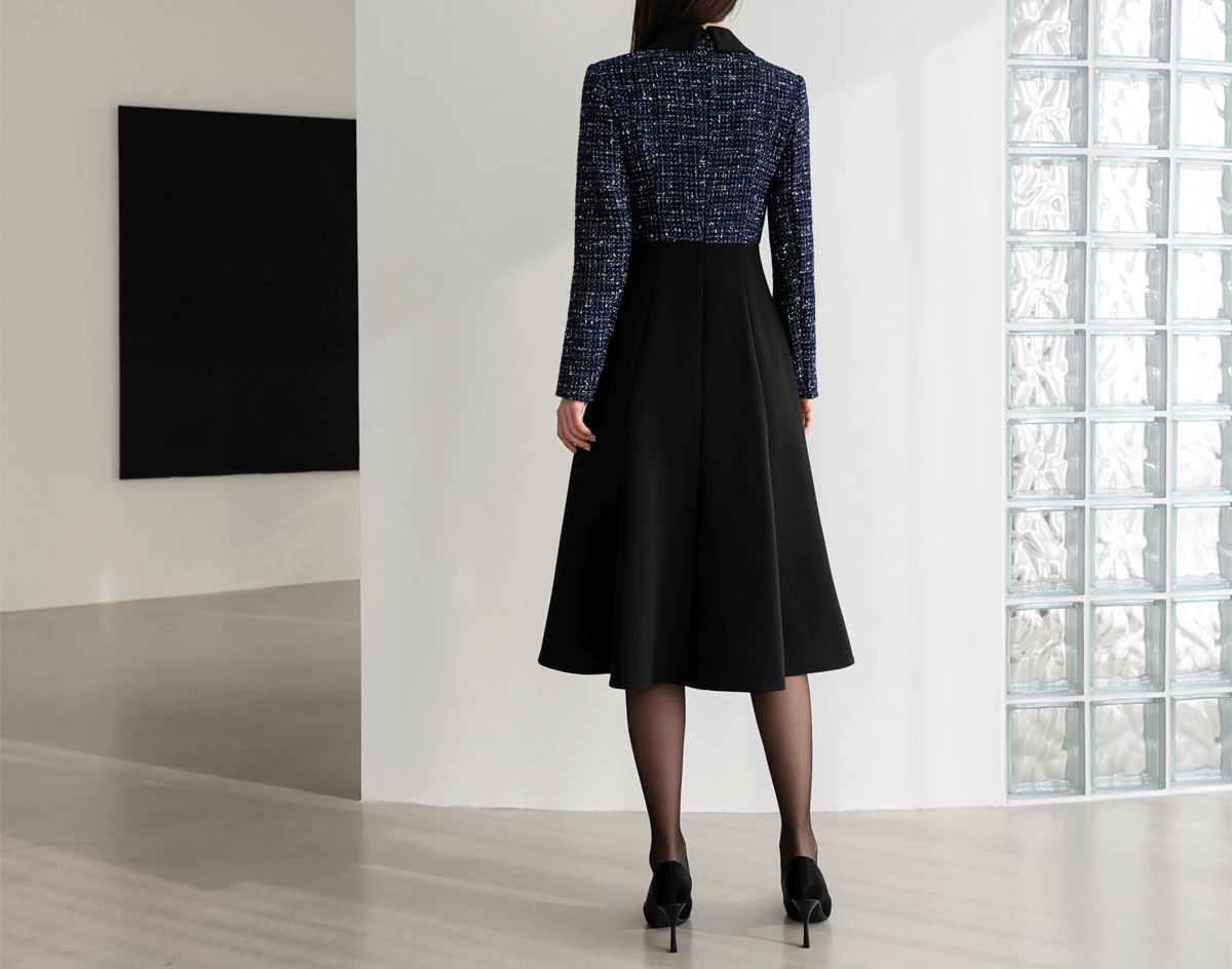 Back view of a two-tone navy tweed and black flare dress with gold button detail, showcasing elegant design and contrasting textures.
