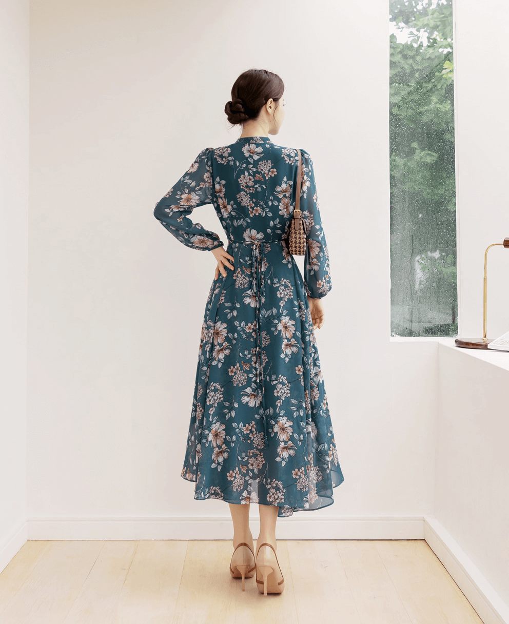 Back view of a woman wearing a floral chiffon flare dress with V-neck and convertible neck tie, styled with beige heels.