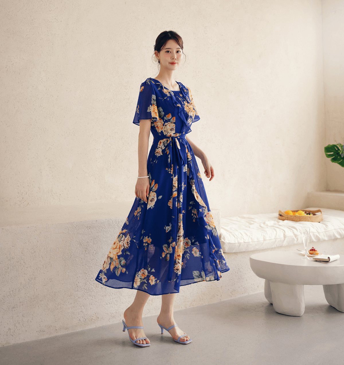 Woman wearing a floral chiffon dress with sheer wing sleeves and square neckline, showcasing an ethereal design and flowing silhouette.