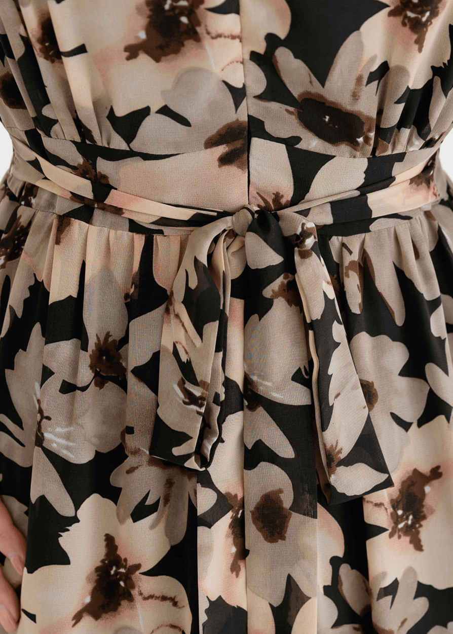 Close-up of floral chiffon dress with cinched waist and delicate flower pattern, emphasizing lightweight fabric and feminine design.