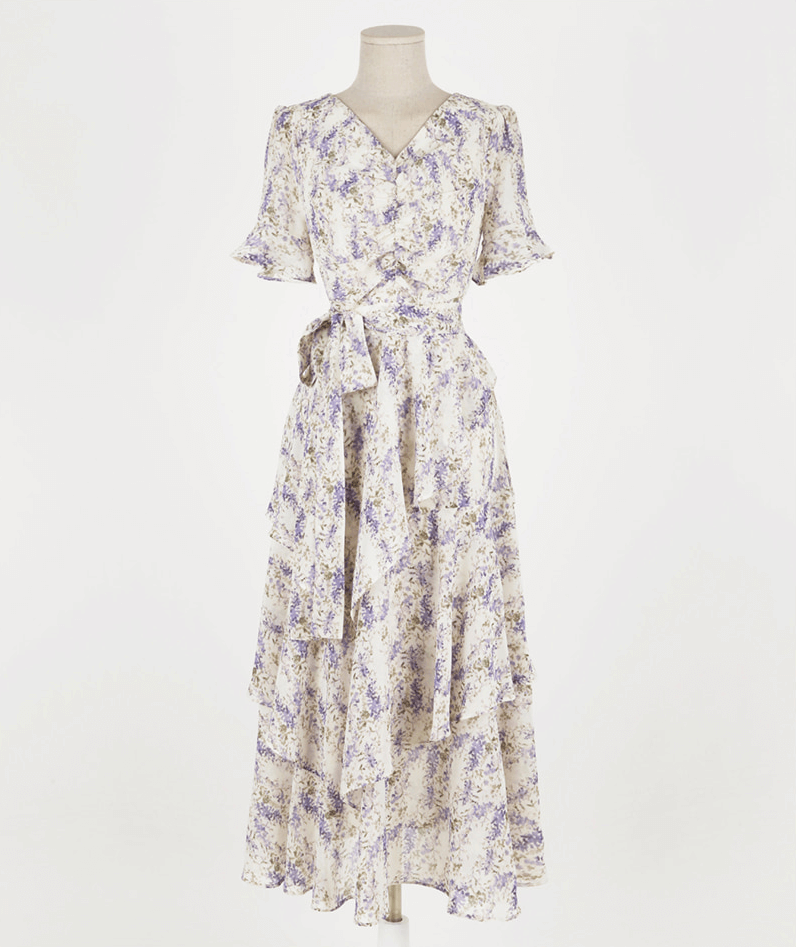 Asymmetrical tiered chiffon dress with purple floral print, V-neckline, puffed sleeves, and ruffled skirt on mannequin, elegant design.