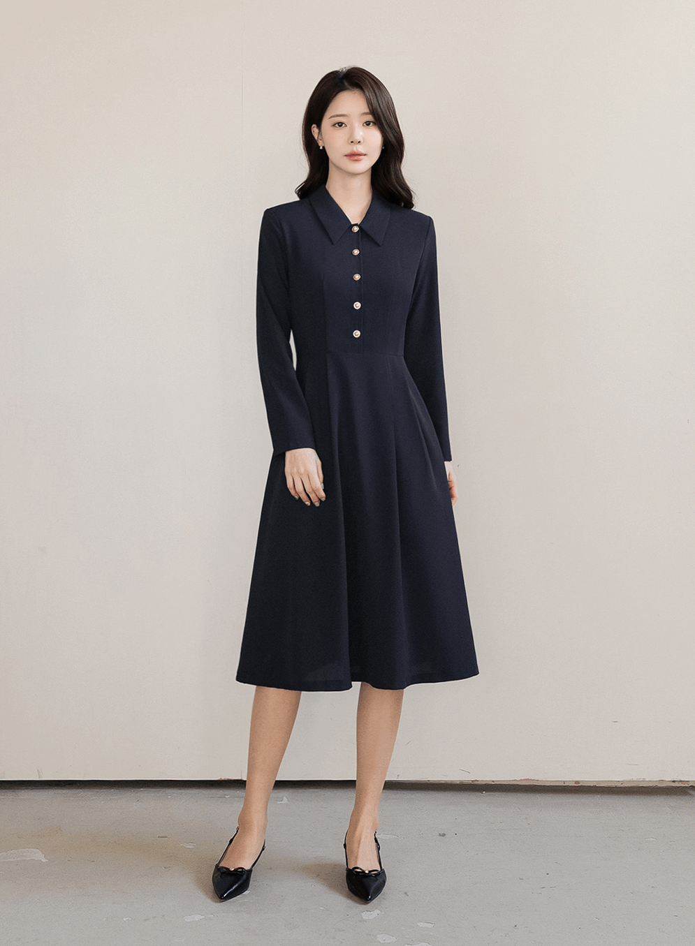 Elegant navy flare dress with long sleeves, structured collar, and belted waistline worn by model, ideal for polished occasions.