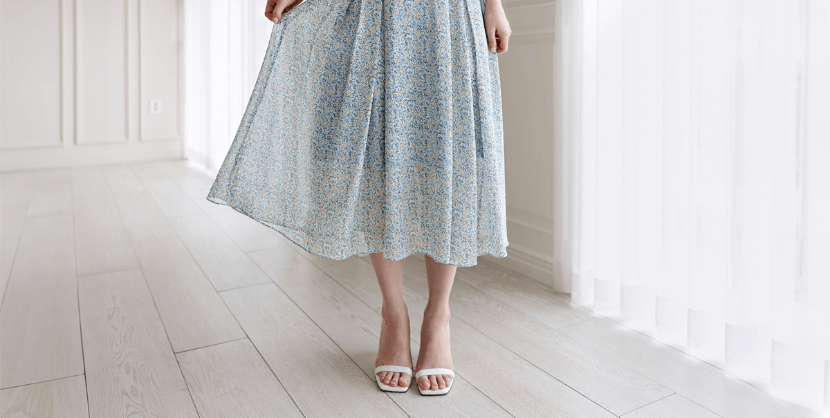 Woman wearing floral chiffon dress with frill collar and waist ribbon, showcasing elegant flow.