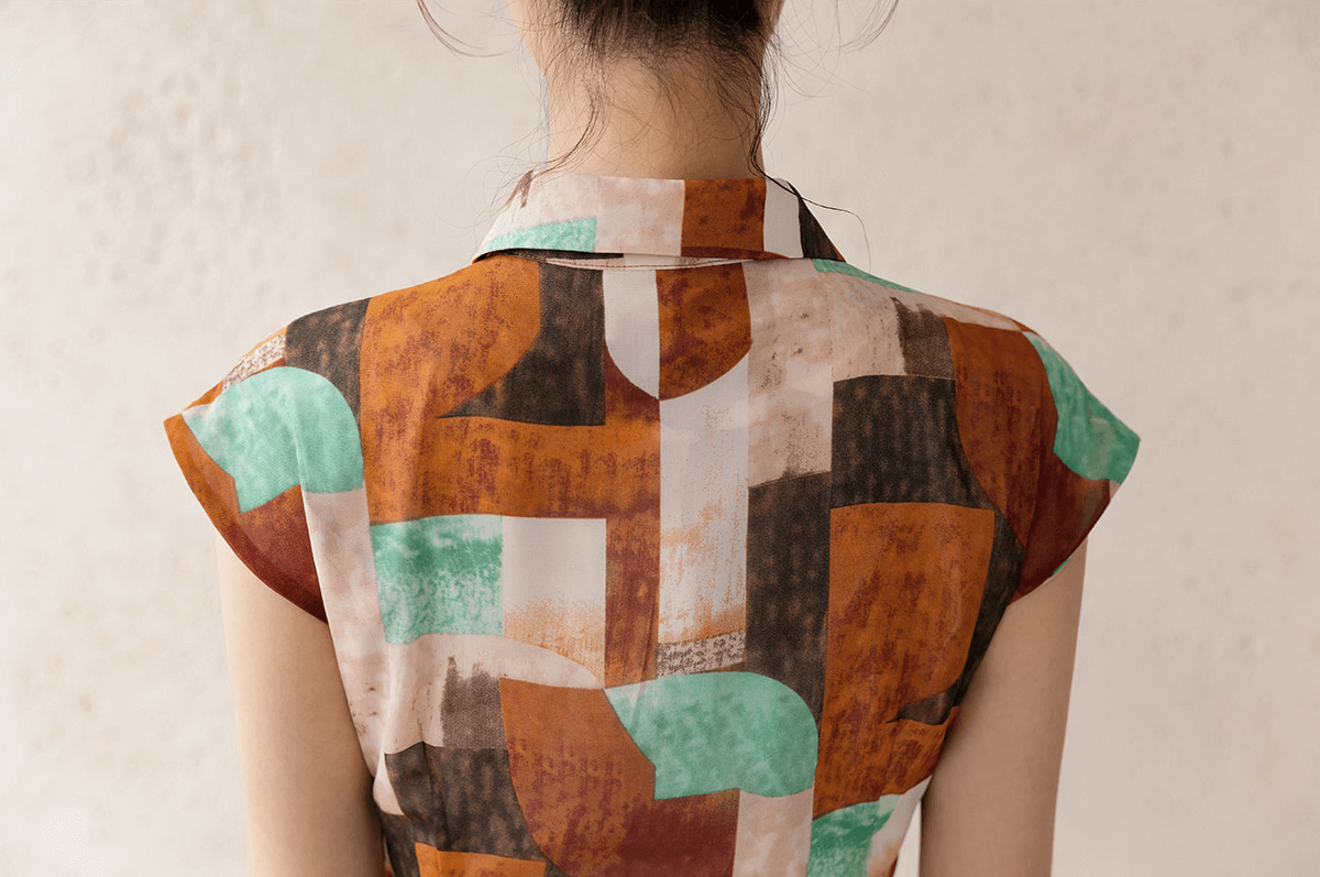 Back view of a vibrant patterned shirt dress with cap sleeves and a classic collar, highlighting elegance and style.
