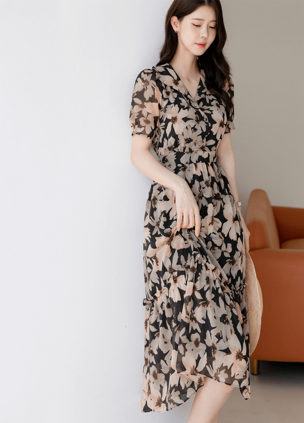 Woman wearing a floral chiffon dress with wide collar and puff sleeves, standing elegantly.