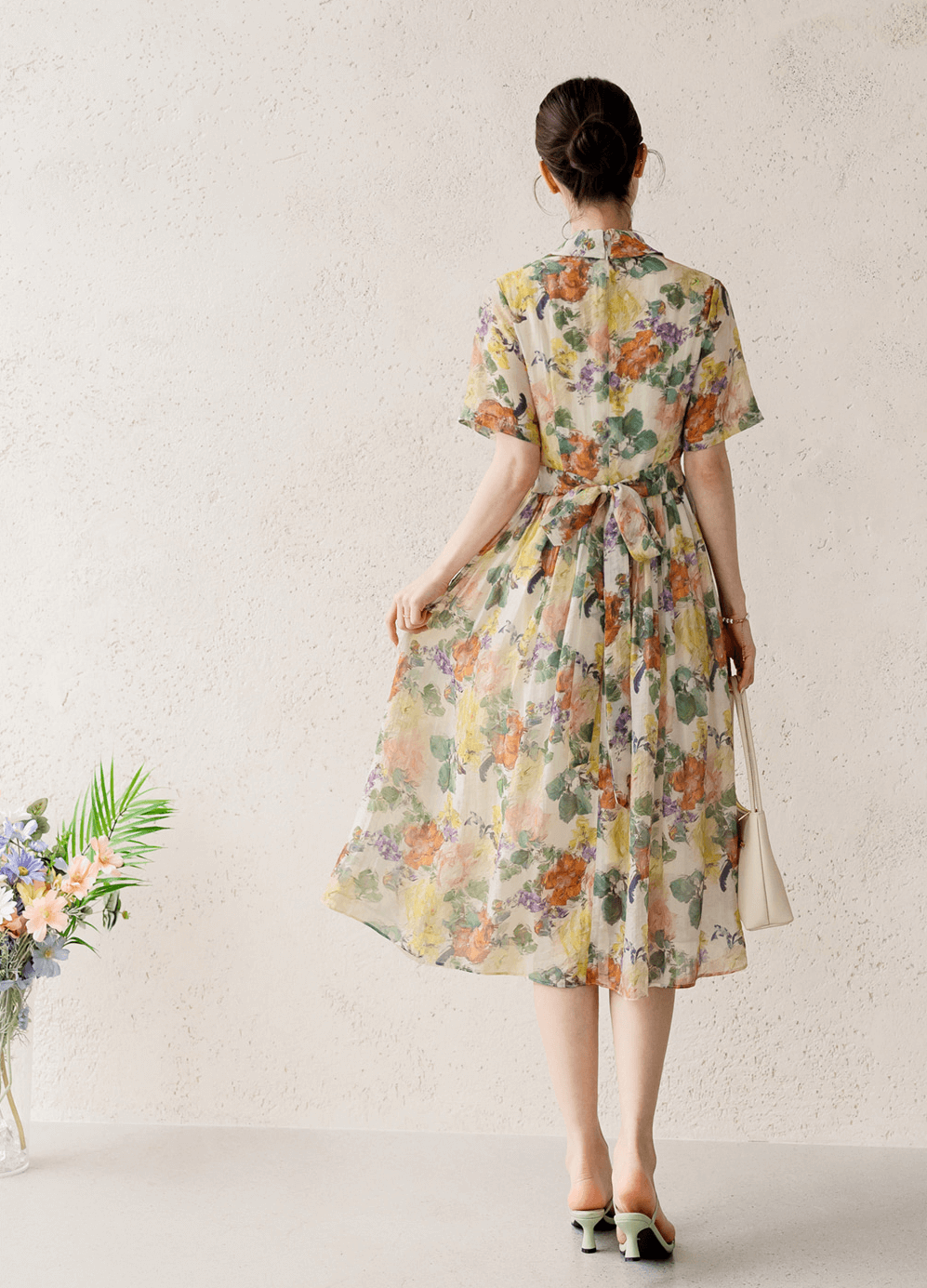 Woman wearing a romantic floral pintuck dress with collar neckline, showcasing elegant, flowing silhouette and subtle floral print.
