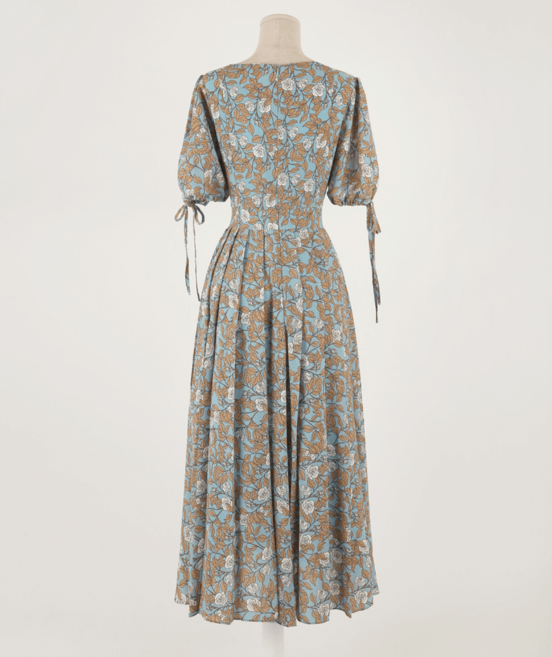 Back view of pleated dress with shoulder-to-hem slit sleeves and ribbon ties, featuring a floral print and A-line shape.