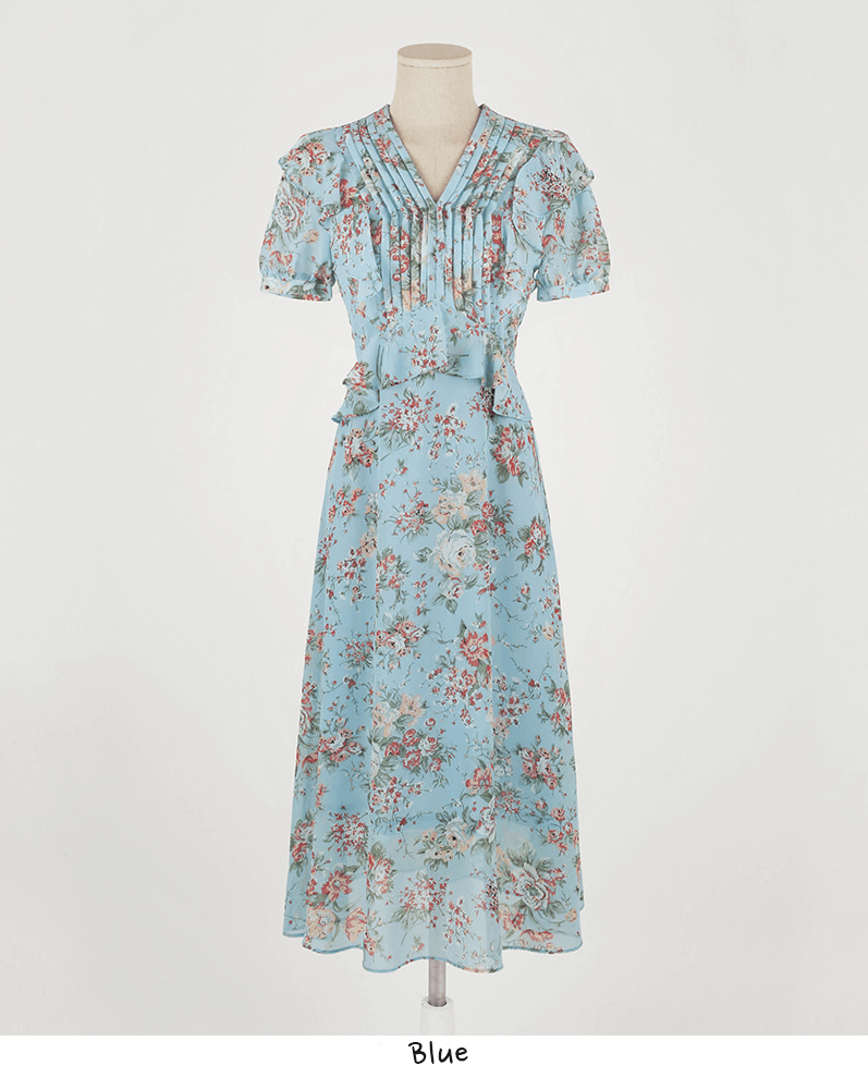 Light blue floral chiffon dress with pintuck bodice, V-neckline, puffed sleeves, and peplum detail on a mannequin.
