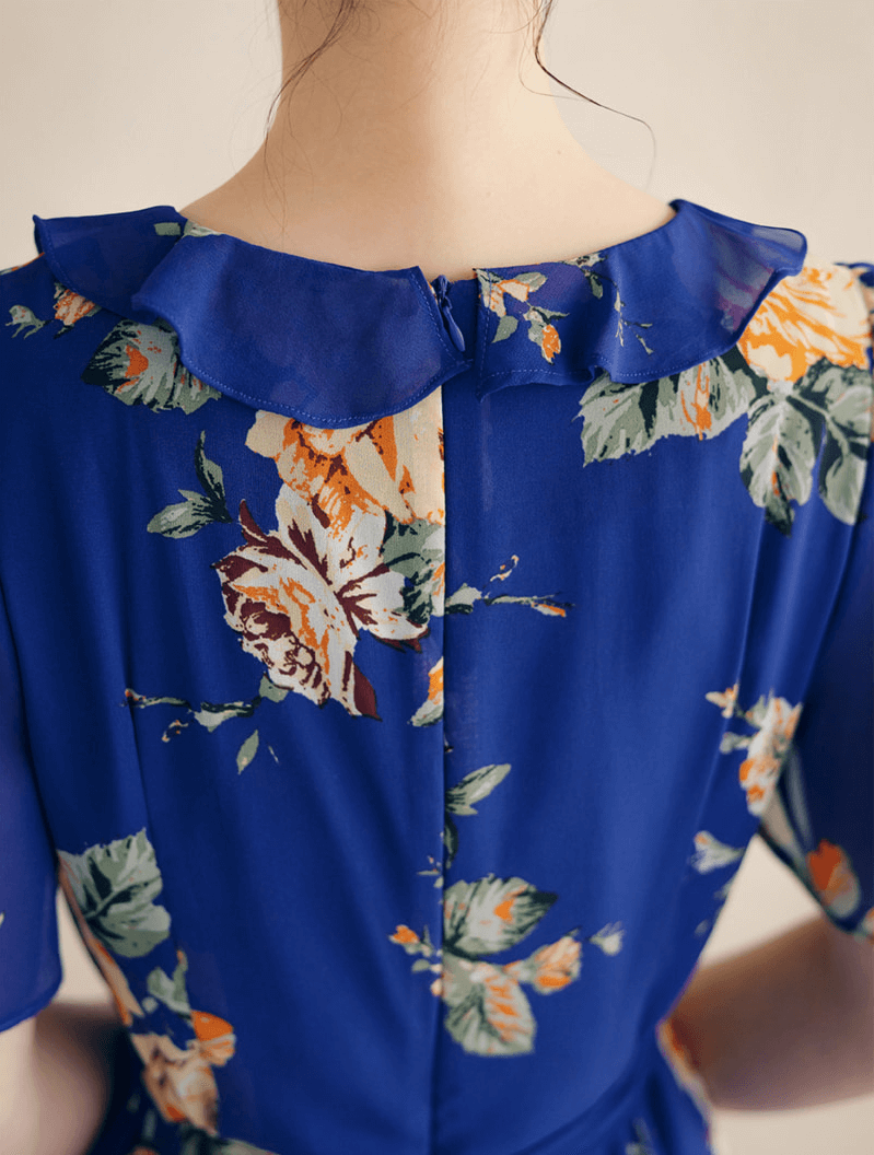 Back view of floral chiffon dress with ruffled neckline and floral pattern on a blue base, showcasing delicate sheer wing sleeves.