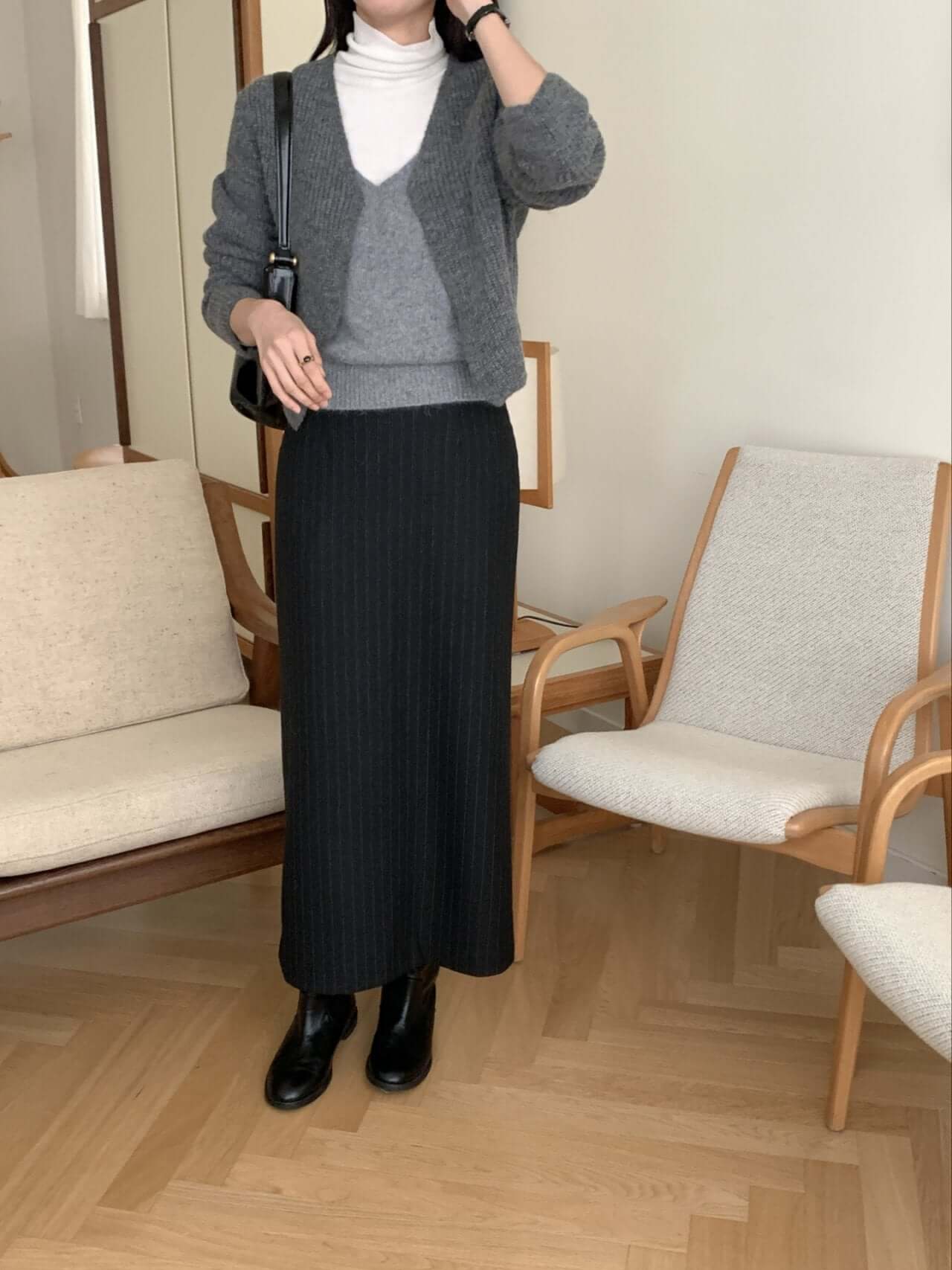 Model wearing a cozy gray alpaca blend cardigan layered over a turtleneck and long skirt, styled for a chic fall look.