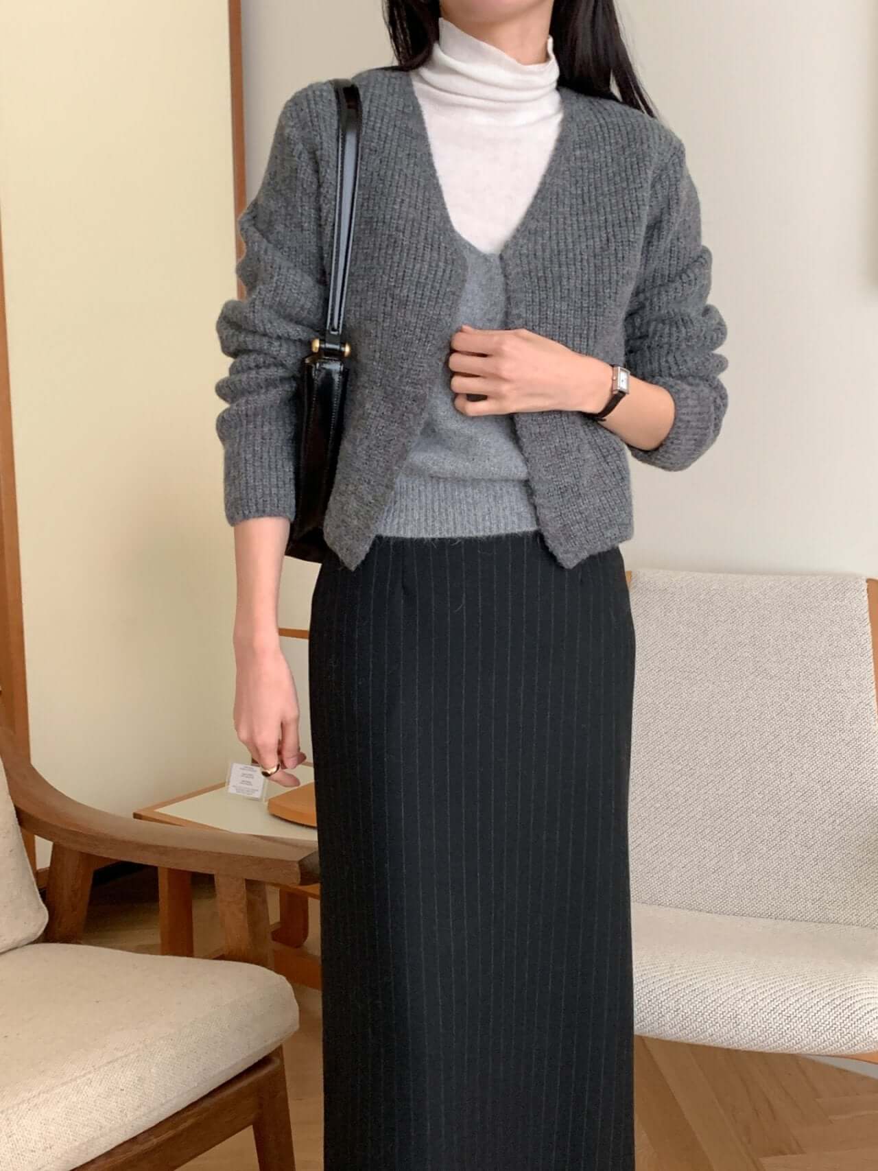 Stylish alpaca blend cardigan in gray layered over a white turtleneck, paired with a black skirt for a chic fall outfit.