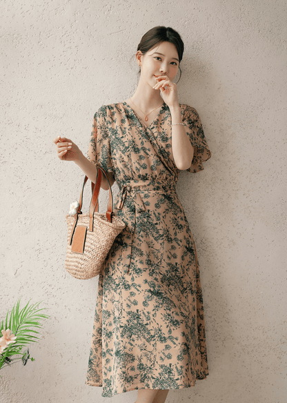 Woman wearing a goddess-inspired wrap dress with graceful wing sleeves, holding a woven bag, showcasing a summer fashion look.