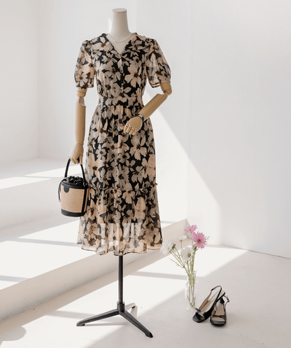 Floral chiffon dress with wide collar and puff sleeves on mannequin, paired with a basket bag and black heels, in a sunlit room.