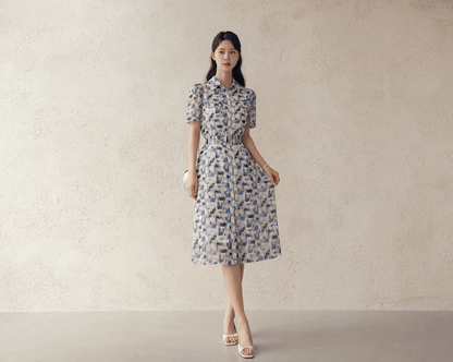 Model wearing breezy chiffon shirt dress with belt, abstract blue and white pattern, collar neckline, and short sleeves, perfect for summer.