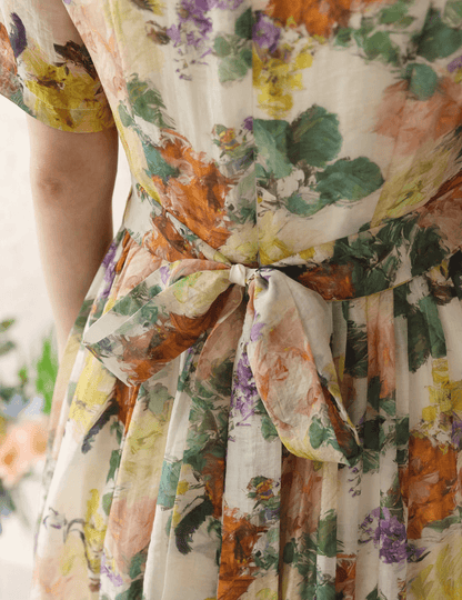 Back view of a romantic floral dress with pintuck detail, featuring vibrant flowers and bow tie, showcasing elegance and feminine style.