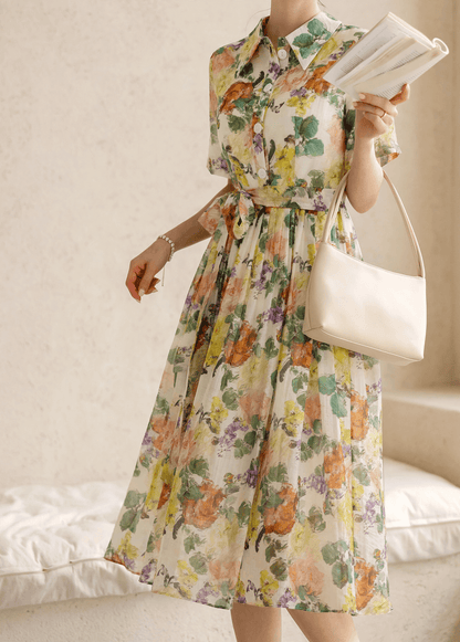 Woman wearing romantic floral dress with pintuck detailing and collar neckline, holding a book and handbag.