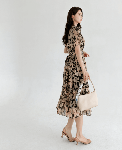 Woman wearing a floral chiffon dress with wide collar and puff sleeves, paired with beige heels and handbag.