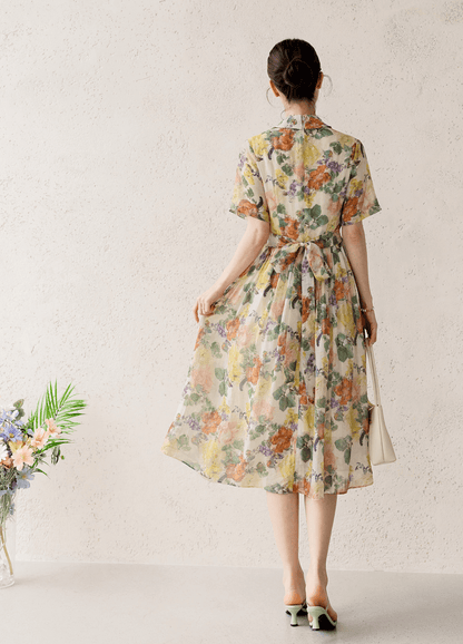 Woman wearing a romantic floral pintuck dress with collar neckline, showcasing elegant, flowing silhouette and subtle floral print.